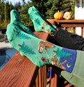[lf] Feet in Bigfoot socks rest on a deck railing, showing forest and night sky patterns.