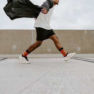 Mid lunge across the concrete deck with the long black robe flaring back, Going Batty For Candy in Orange socks visible on both planted feet. [lf]