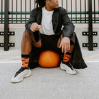 Wider rooftop frame of the same pumpkin perch, the model gazing off as Going Batty For Candy in Orange socks balance the orange gourd at his sneakers. [lf]