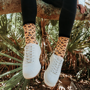 A friend laughs at a brunch table, modeling Leopard Print socks in Gold above ankle boots. [lf]
