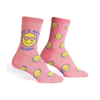 Crew socks in pink with glitter.  The design features yellow smiley faces and the phrase 'Be a Nice Human' on one sock.