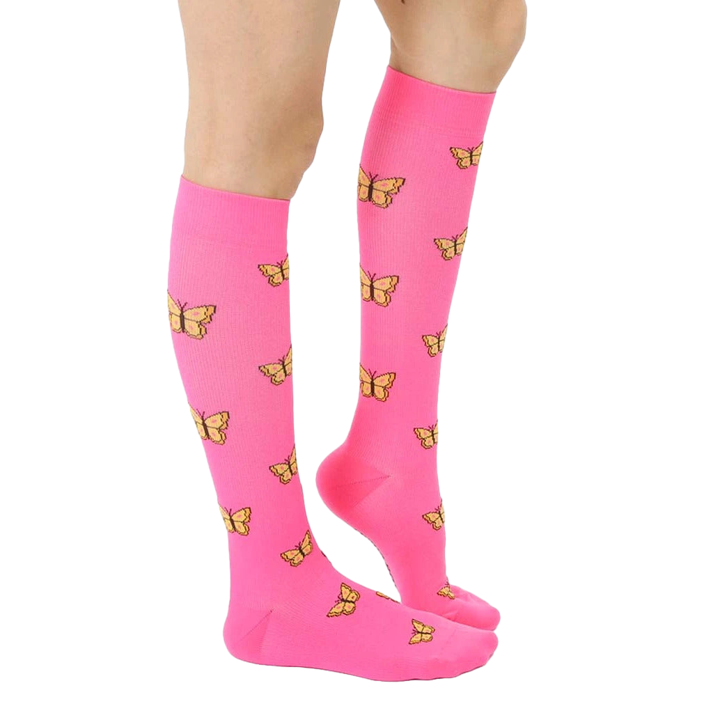 Side view of pink knee-high socks with yellow butterfly pattern worn on a person's leg. [lf]