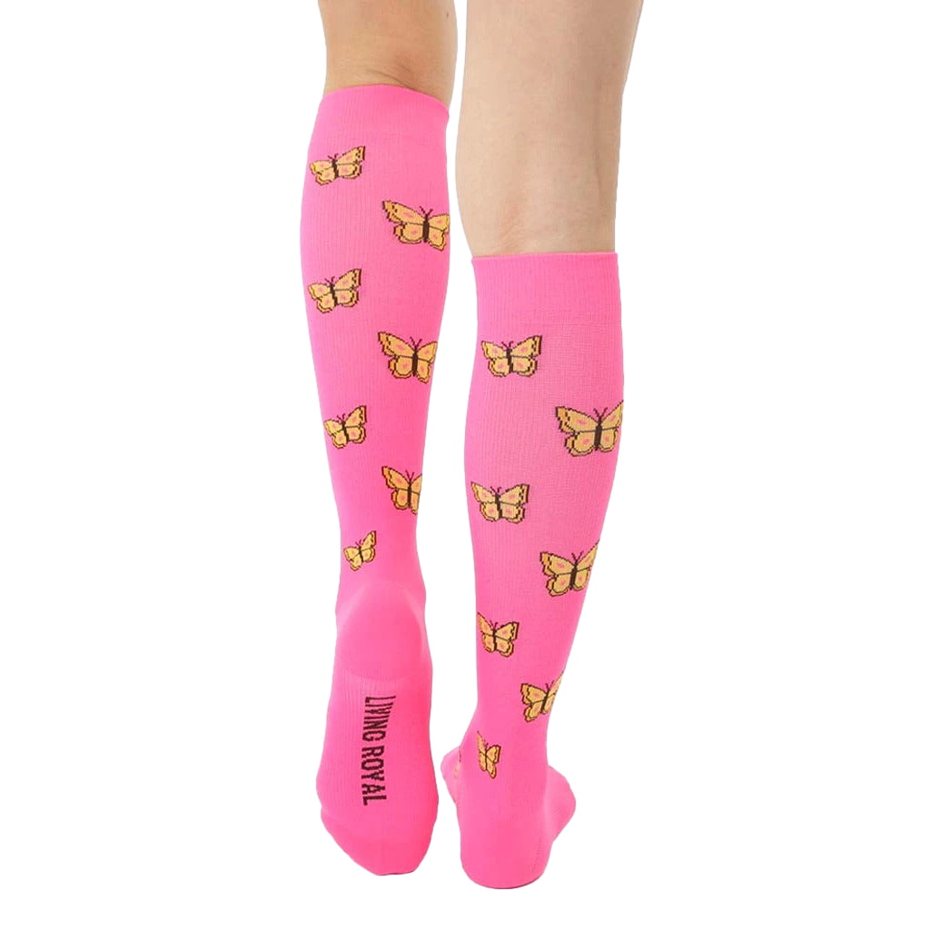 Rear view of pink knee-high compression socks displaying yellow butterflies and a small logo near the heel. [lf]