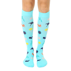 Pair of aqua blue knee-high compression socks.  A whimsical under-the-sea pattern with colorful whales, crabs, starfish, and stingrays is shown. [lf]
