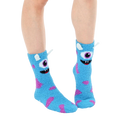 Lifestyle shot of light blue fuzzy monster slipper socks worn on a person's feet. [lf]