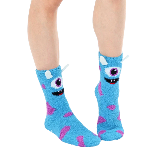 Lifestyle shot of light blue fuzzy monster slipper socks worn on a person's feet. [lf]