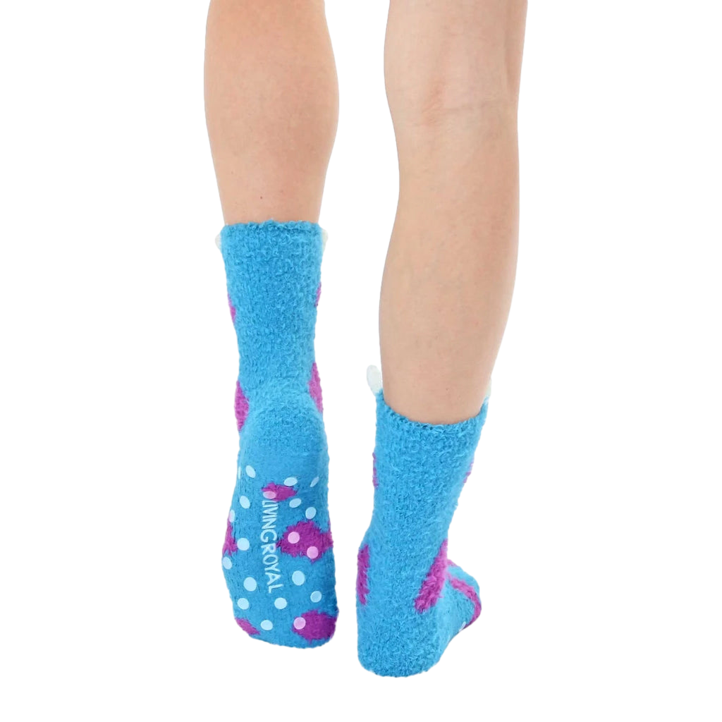 Close-up view of the back of the light blue fuzzy monster slipper socks, showing the non-skid grips on the soles. [lf]