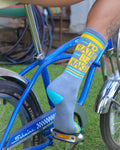 Lifestyle shot of a person's leg wearing a 'I'd Rather Be Naked' sock while sitting on a blue bicycle. [lf]