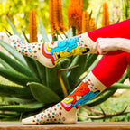 Lifestyle shot of 'Star Gazing' socks on a model's legs against a garden backdrop. [lf]