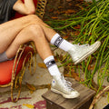 Lifestyle shot: A person's legs wearing the 'Dick' socks and silver Converse sneakers. [lf]