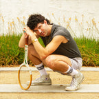 Lifestyle shot: A person wearing the 'Dick' socks and silver Converse sneakers, holding a tennis racket. [lf]