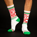 Lifestyle shot of a person's legs wearing the "Merry Fitmas and a Happy New Rear" socks against a black background. [lf]