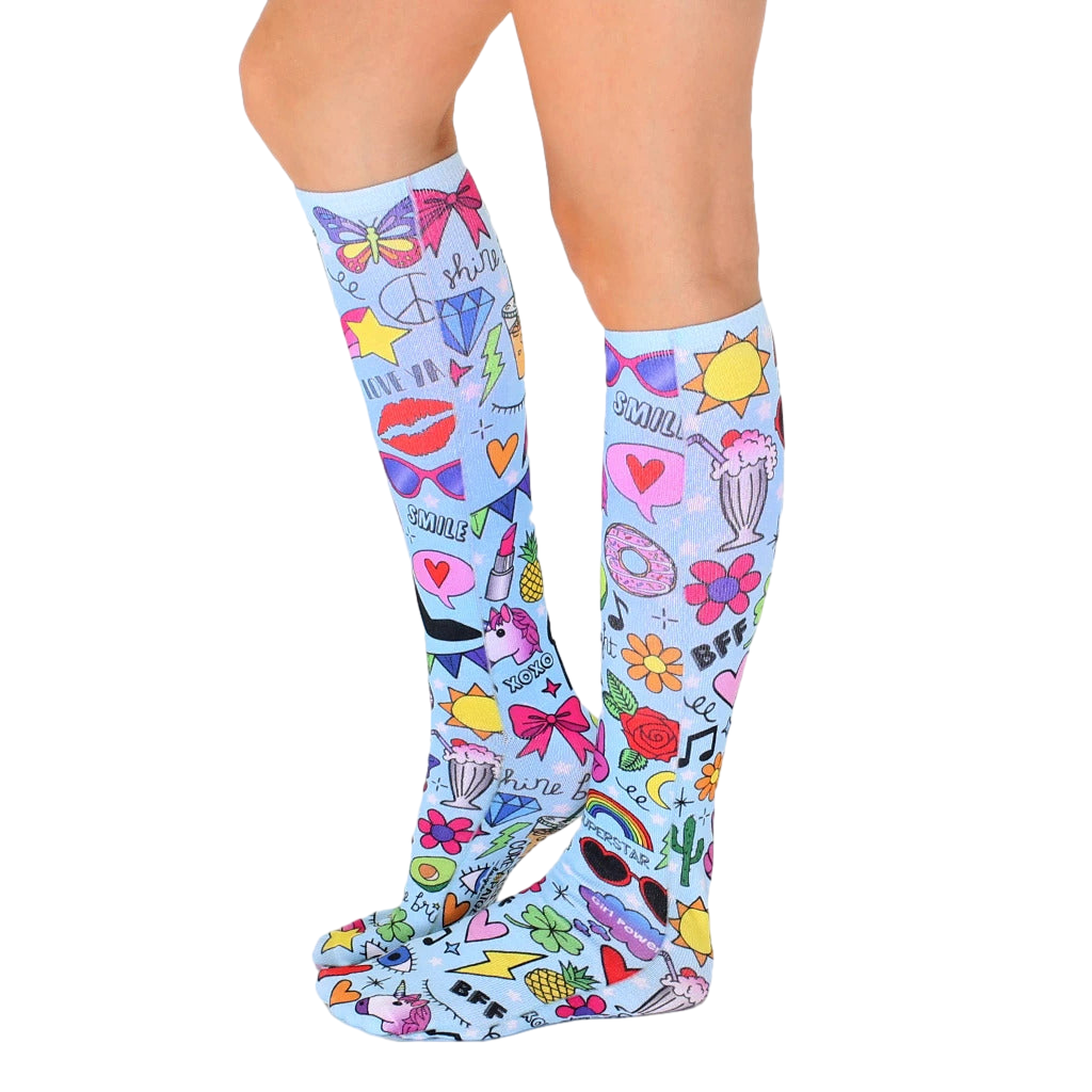 Glam Girl knee-high socks shown on a model's legs. The socks feature a light blue background with a playful, colorful design. [lf]