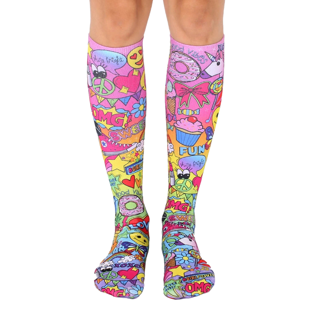 Pair of knee-high socks. Pink base with colorful cartoon designs, including unicorns, cupcakes, and peace signs. [lf]