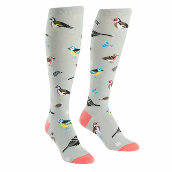 A pair of women's knee-high socks in light gray with a pattern of colorful birds and leaves. Coral-colored heel and toe.