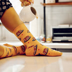Lifestyle photo of a person wearing the pancake socks; syrup is being poured from a small pitcher onto the socks. [lf]